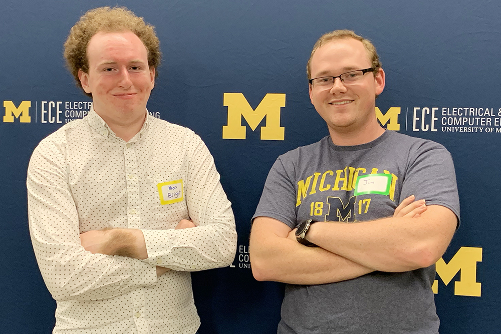 Two guys pose in front of U-M ECE backdrop